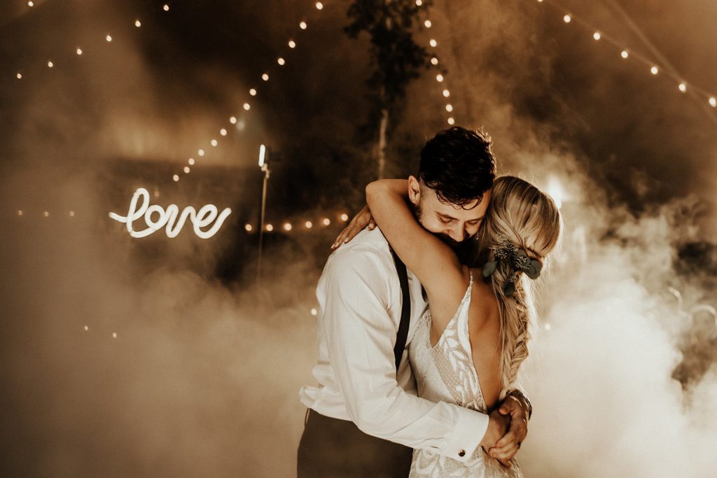custom neon sign behind bride and groom during fog first dance at West Chester KOA wedding reception