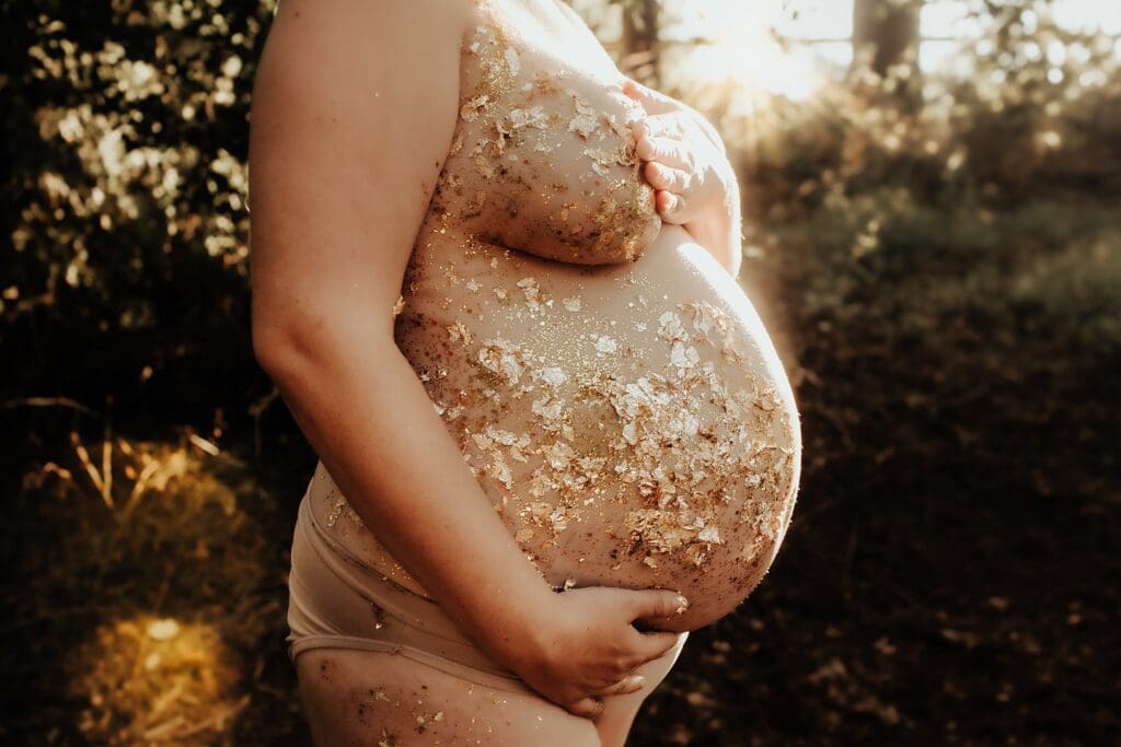 Pregnant woman holding her belly in the woods during an outdoor maternity photoshoot